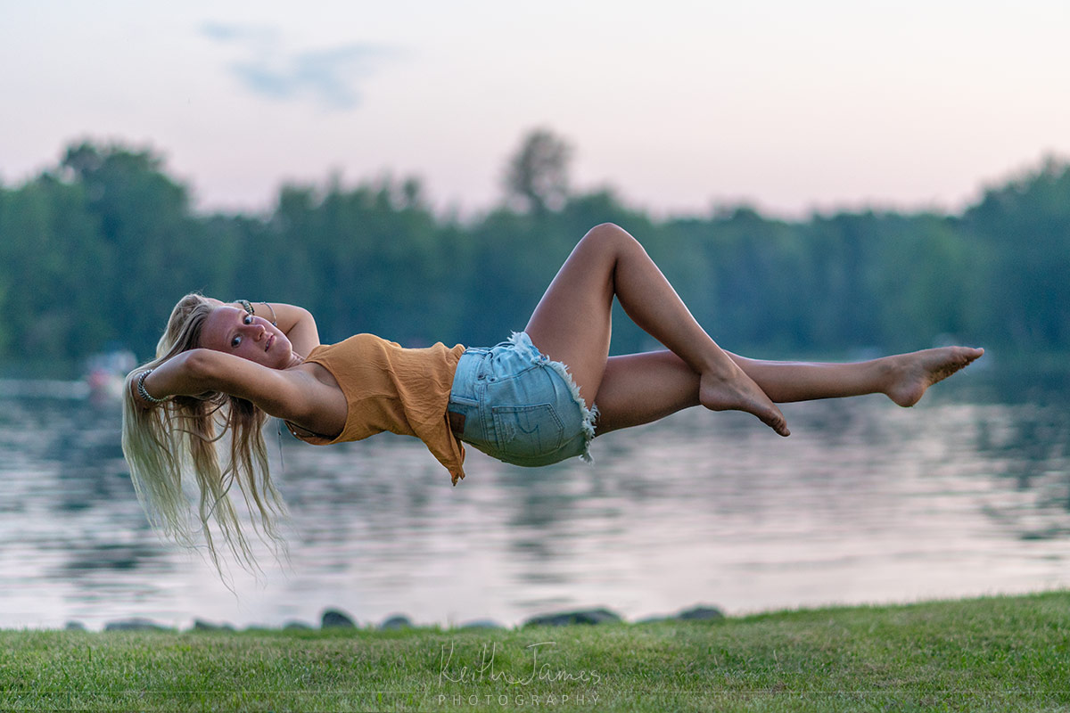 Levitation photography: A lovely blonde young woman reclines in mid-air near a lake.